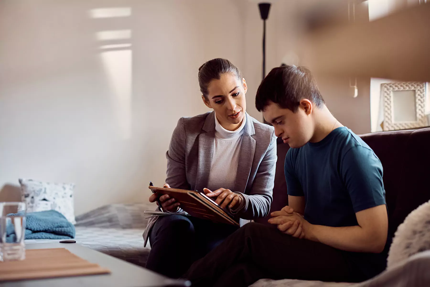 Disabled man sitting on couch looking at iPad with support worker