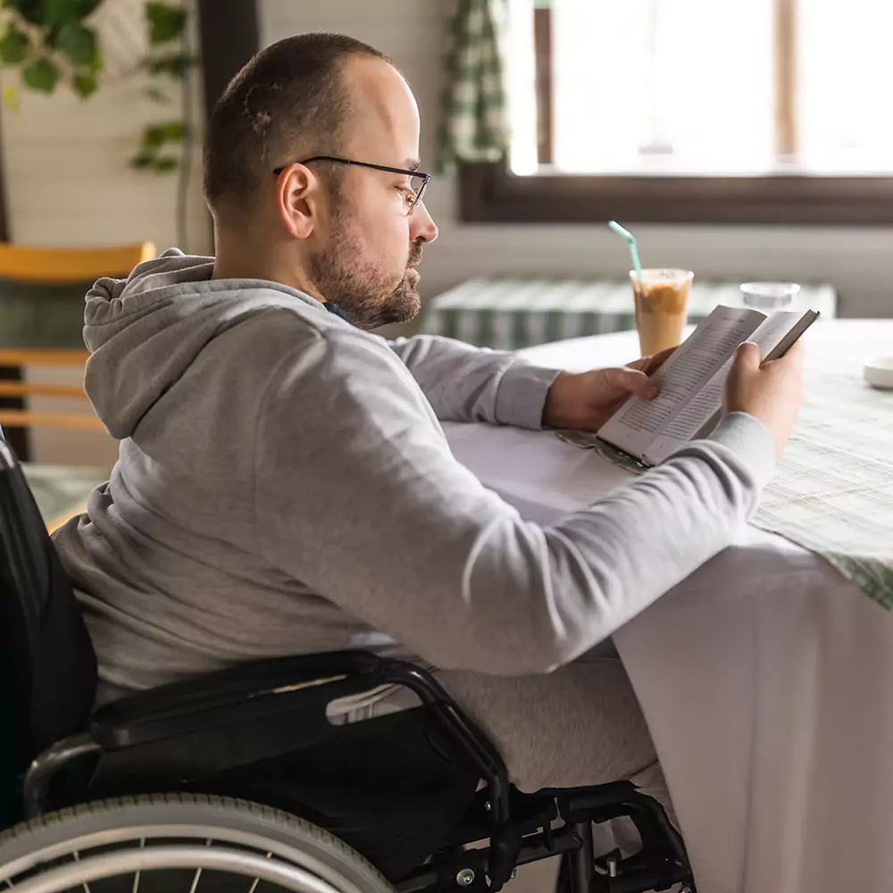 Quadriplegic man reading a book in a cafe