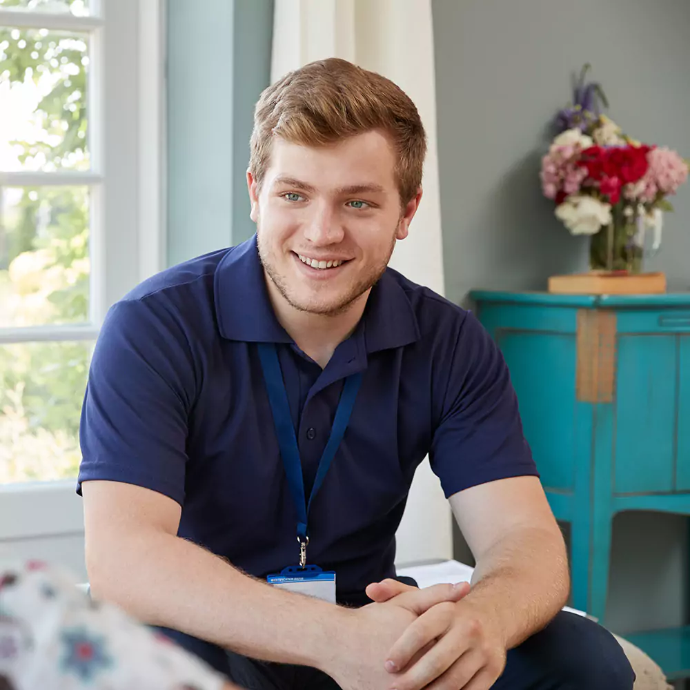Happy male nurse in home with participant